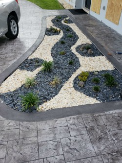 Decorative river-rock landscape design on a stamped-concrete driveway